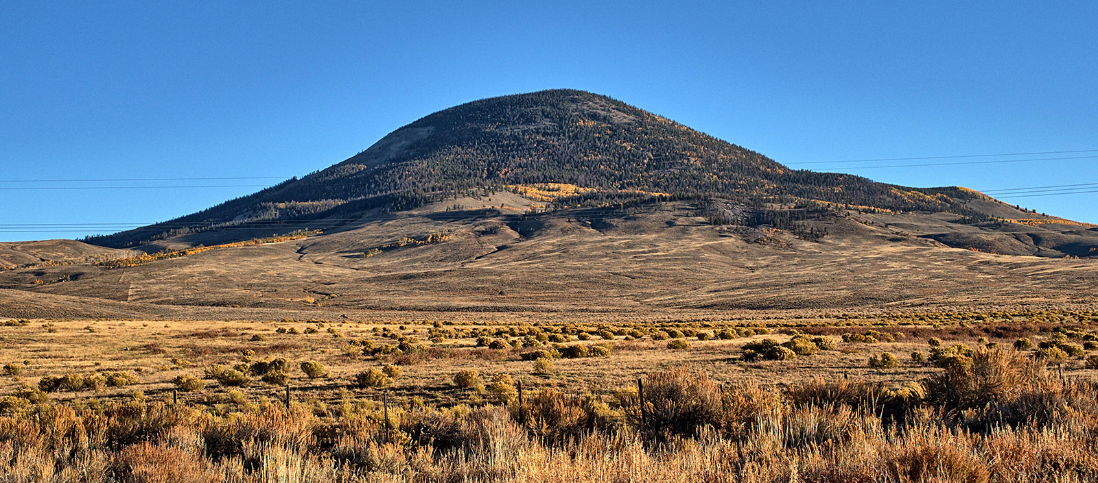 Tomichi Dome, a Tertiary laccolith, formed when magma was forced out through and above Cretaceous Dakota sandstone and into Mancos shale to form a dome.  Sandstone and shale were subsequently eroded away.  West of Sargents CO on US Highway 50.