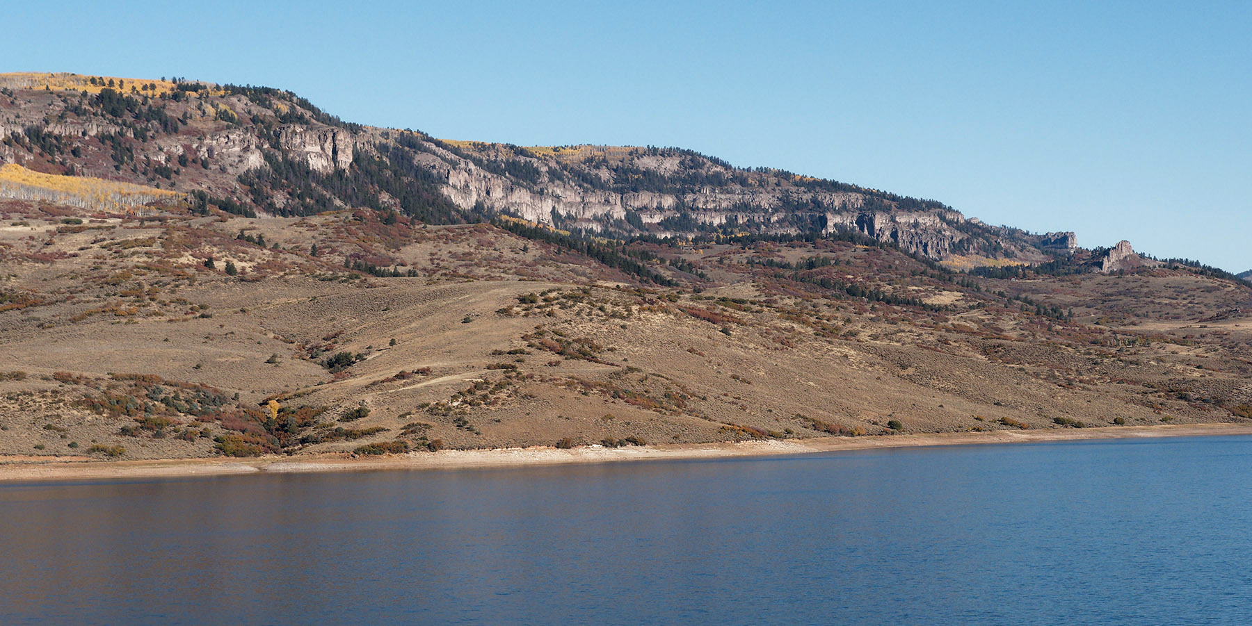 Terraced layers of rhyolitic brecca and tuff above Mesozoic sediment by Blue Mesa Reservoir.