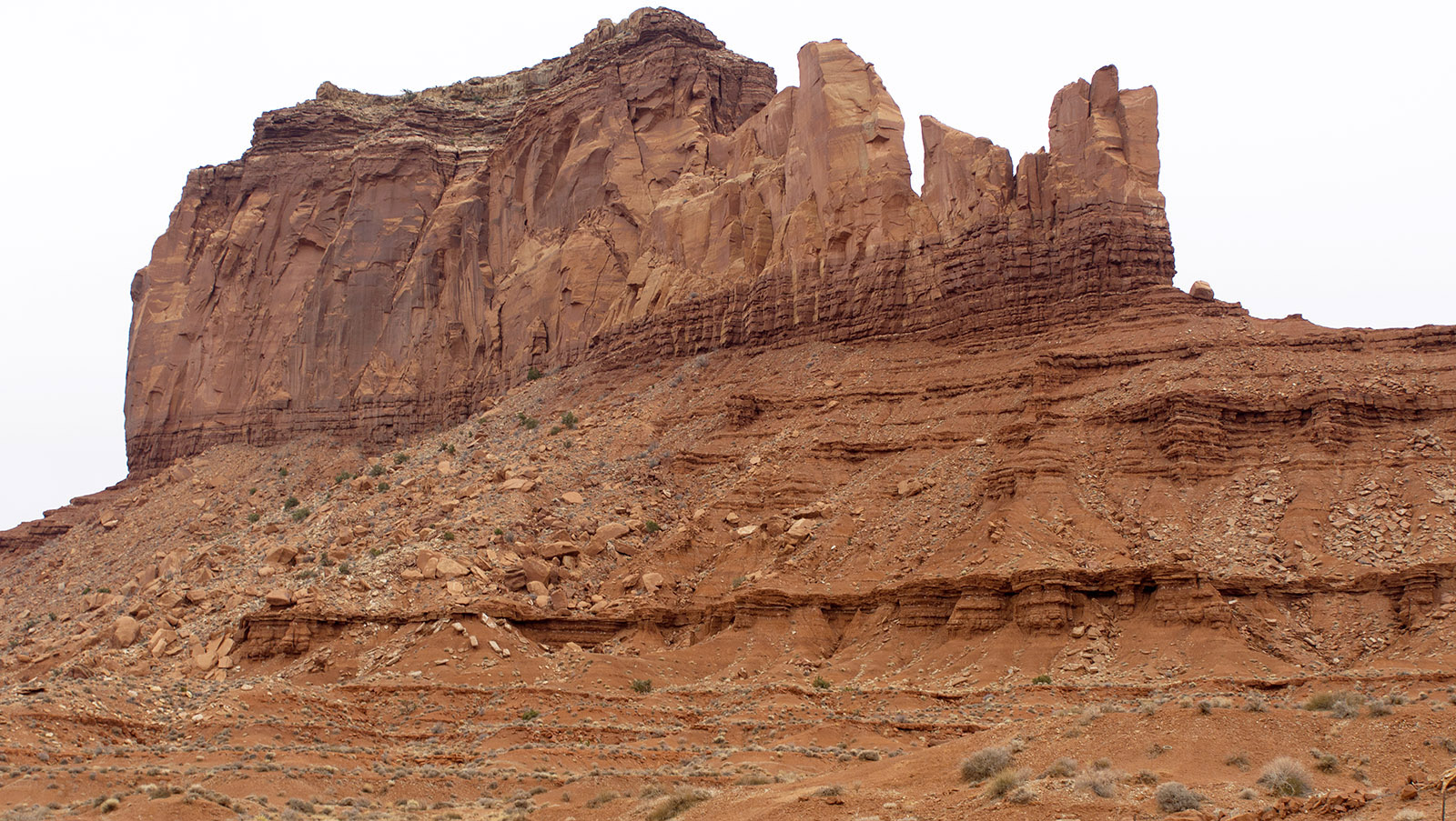 Detail of Monument Valley formation: Base of organ rock shale from 290 million years ago (early to mid Permian), thick hard band of DeChelly sandstone (280 million years); topped by cap of conglomerate of eroded sandstone and pebble Shinarump member of the Chinle Formation (225 million years)