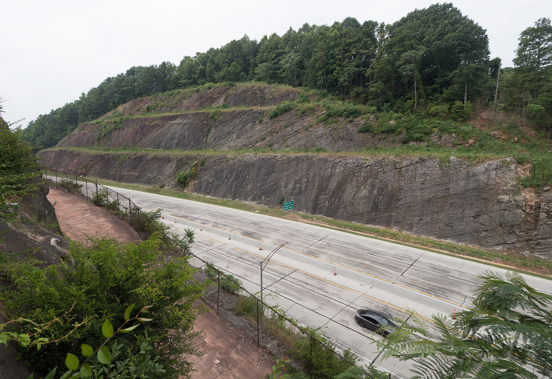 This is the Red Mountain Expressway road cut for US Highway 31 and 280 in Birmingham, Alabama which reveals the stratigraphy of weathered sedimentary layers laid down from 485 to 420 million years ago and folded and tilted into an anticline.  The geology of the road cut is described in detail in:  Lancefield, J.  Lost Worlds in Alabama Rocks.  A Guide to the State’s Ancient Life and Landscapes.  2nd Ed, The Alabama Museum of Natural History, 2018.