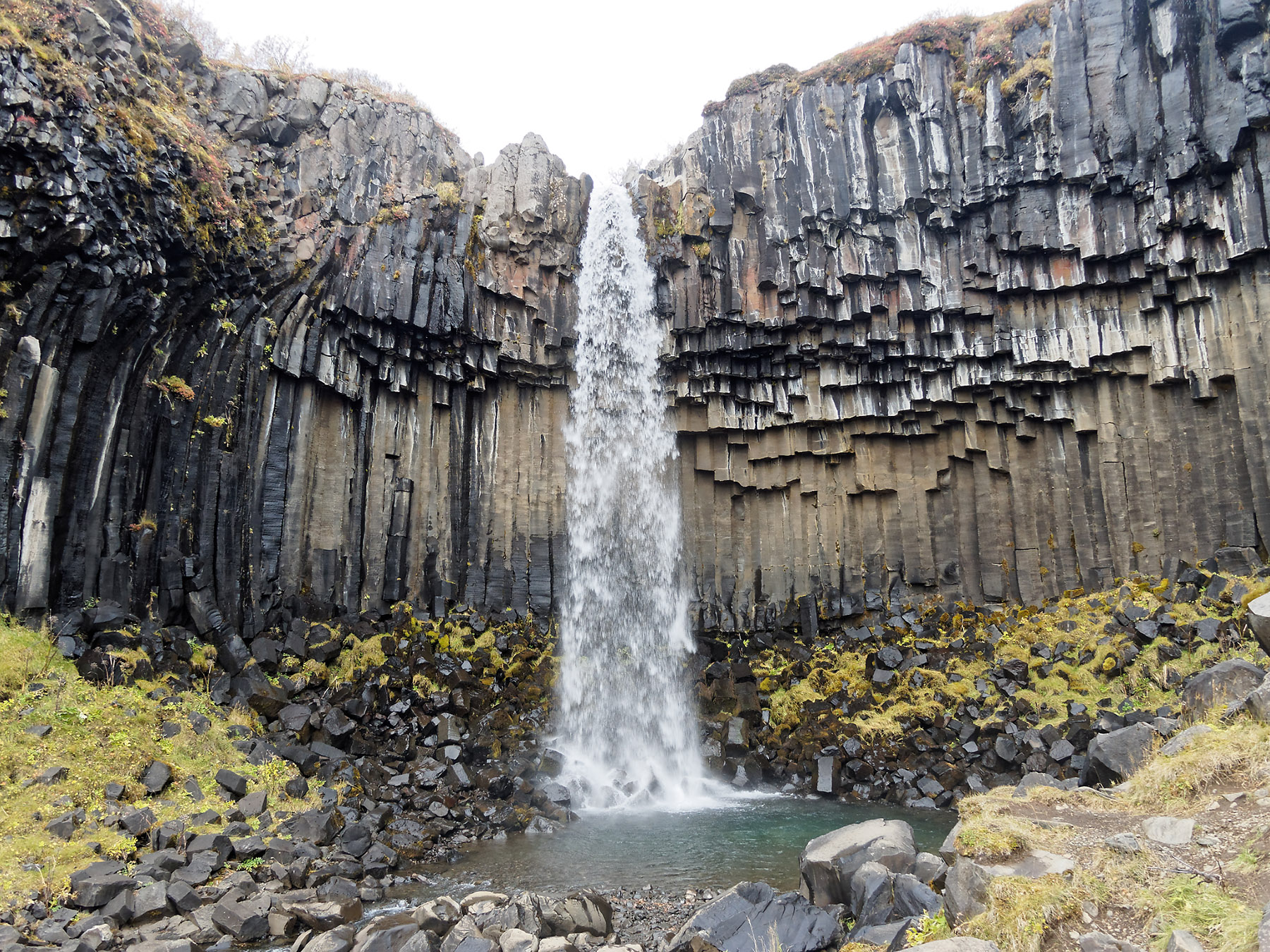 Svartifoss, the Stórilækur river drops 20m off a cliff of black columnar basalt.  The vertical orientation of the columnar basalt suggests that this was an intrusive volcanic sill or volcanic outcrop that was subsequently exposed by the erosive activity of the river.  Lava flows are reported to be from the Upper Pleistocene (<0.8 Ma).