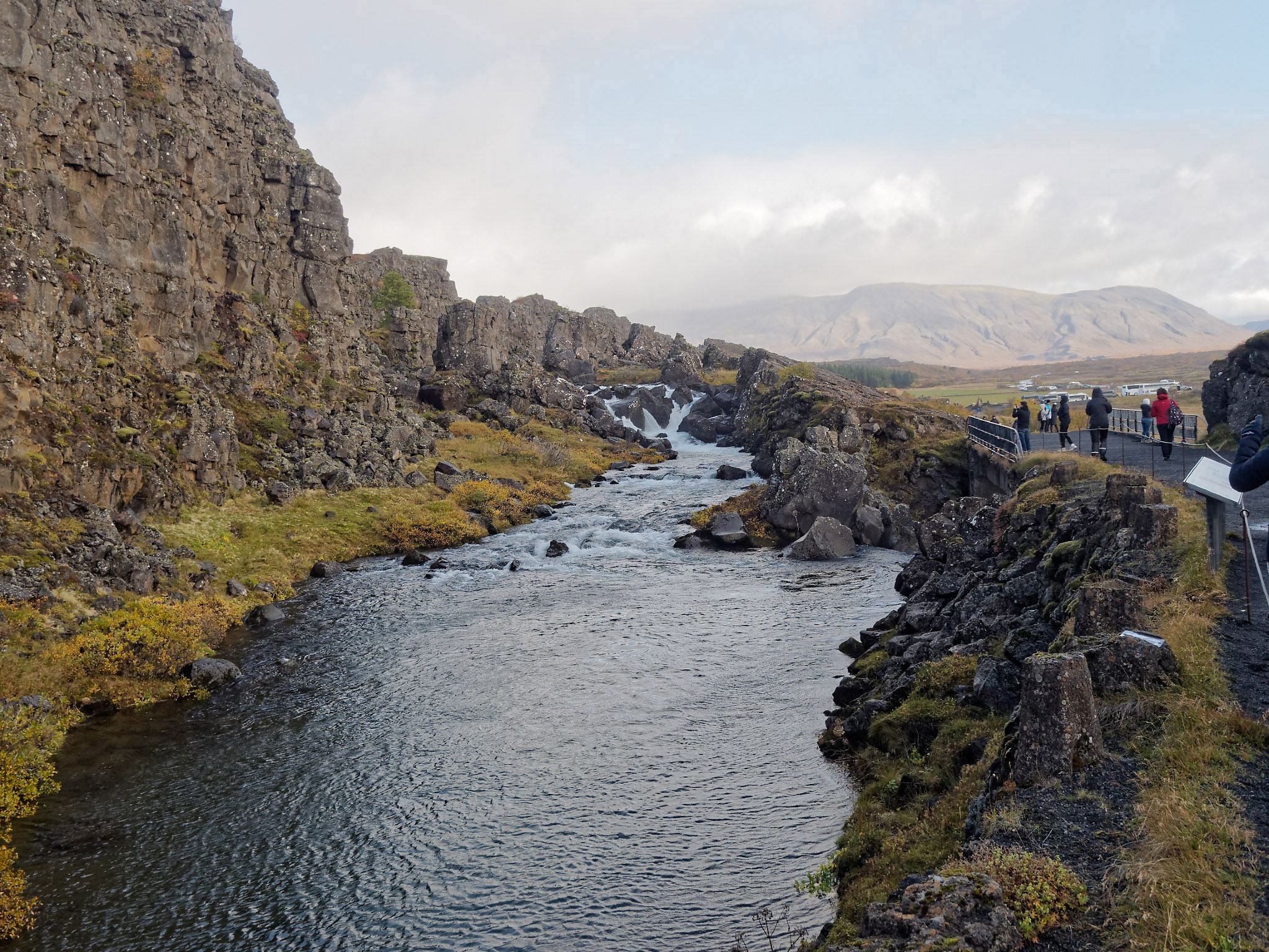Waterfall and deep pool bordered on left by stratified basalt layers from multiple lava flows and separation along the fault line. Þingvellir National Park. The area is included in the site where Alþingi, the world’s oldest running parliament was founded 1000 years ago. The deep pool in the foreground (Drekkingarhylur) was where Christian-influenced legal practices between 1565 and 1739 resulted in at least 18 women being sentenced to death for adultery, incest or infanticide. They were forced into a bag and drowned by submersion in the pool. Men convicted of the same offences were beheaded (a male body count isn’t available.)