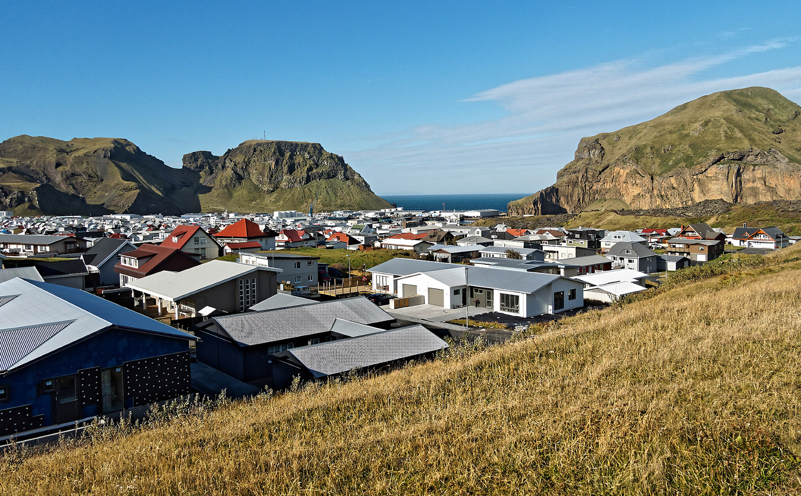 Newly constructed and rebuilt houses at the foot of Eldfell on Heimaey. On the far right of the field is Heimaklettur, the largest mountain on the island that has steep cliffs to the ocean.