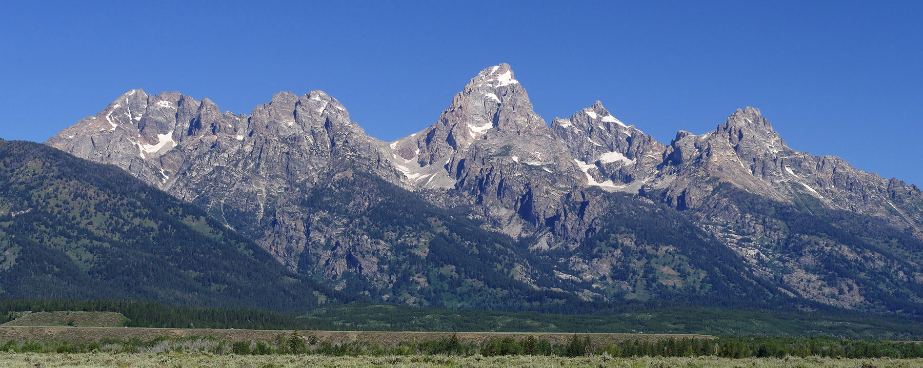 The Cathedral group of the Grand Tetons rose along a normal fault over the last 5 million years and were sculpted to their sharp angular form by glaciers over the last 2 million years with the last major glaciers receding 15,000 years ago.  They are composed largely of quartz monzonite (a type of granite) which was the core of a previous mountain range that was raised by tectonic compressive forces 55 million years ago and then eroded.  This metamorphic core of the mountains arose originally from volcanic and sedimentary rocks 2-3 billion years ago.