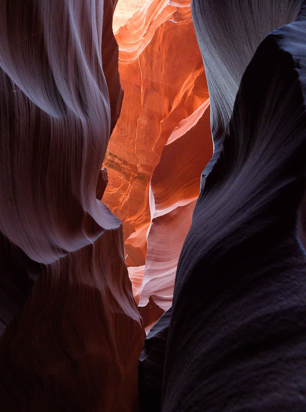 Lower Antelope Canyon is a slot canyon formed by millions of years of water and wind erosion in Navajo sandstone that formed during the Jurassic Period during arid weather.   Flash floods account for the tortuous rounded surfaces.  The fine gradations are further weathered by wind-blown sand through the canyon.